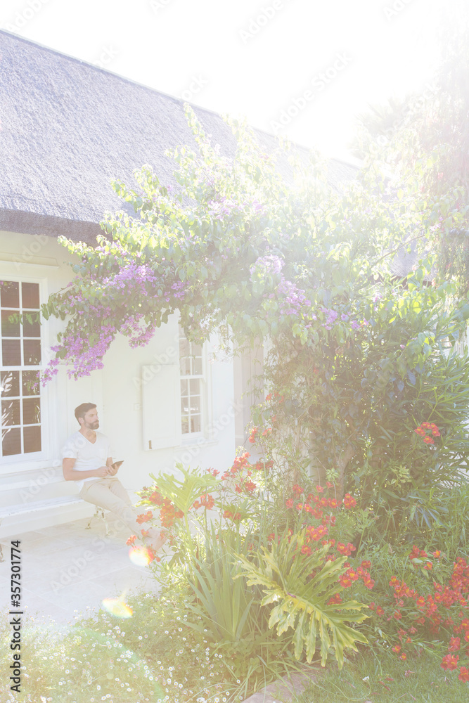 Man on porch admiring flowers in backyard