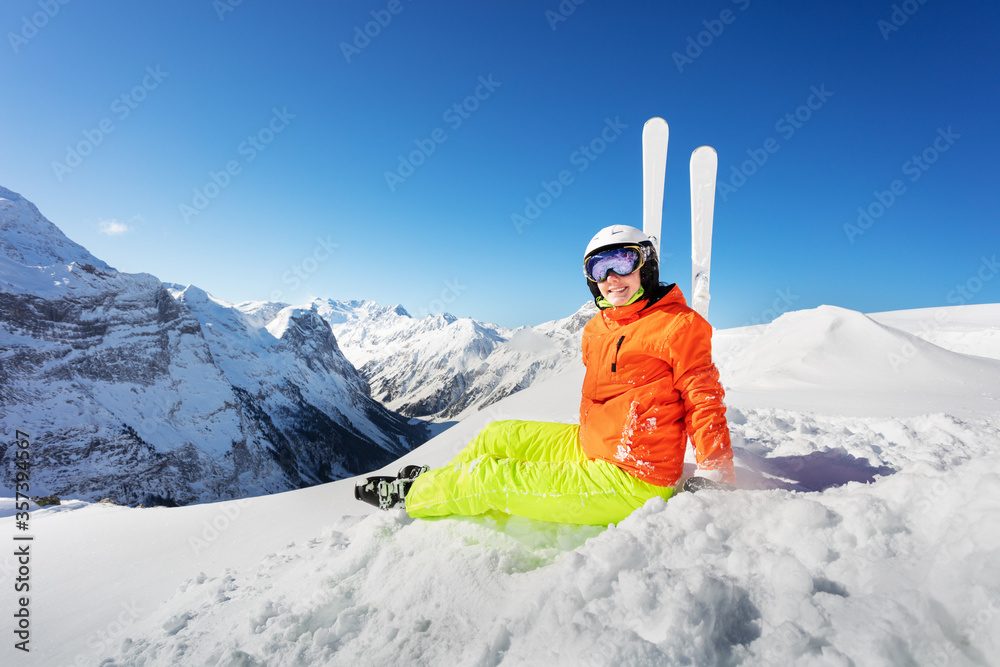 穿着亮橙色运动服在高山度假胜地雪地里滑雪的少女