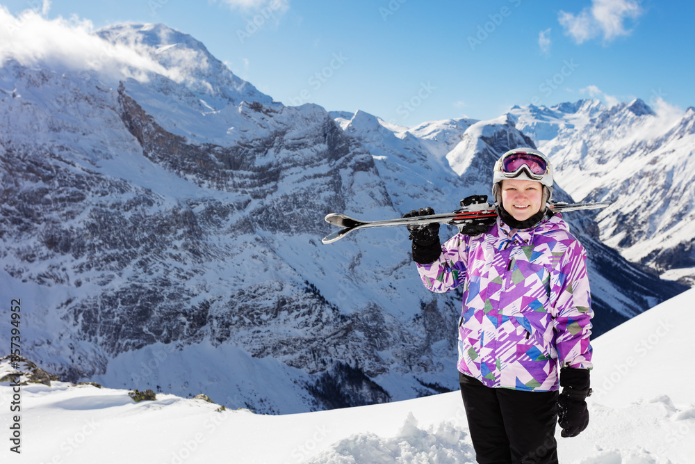 Smiling portrait on top of the mountain of girl skier sportsman stand and hold ski on the shoulder o