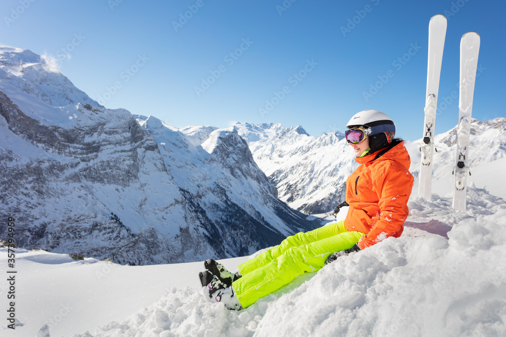 穿着橙色明亮运动服的少女，在高山山峰和蓝天上滑雪