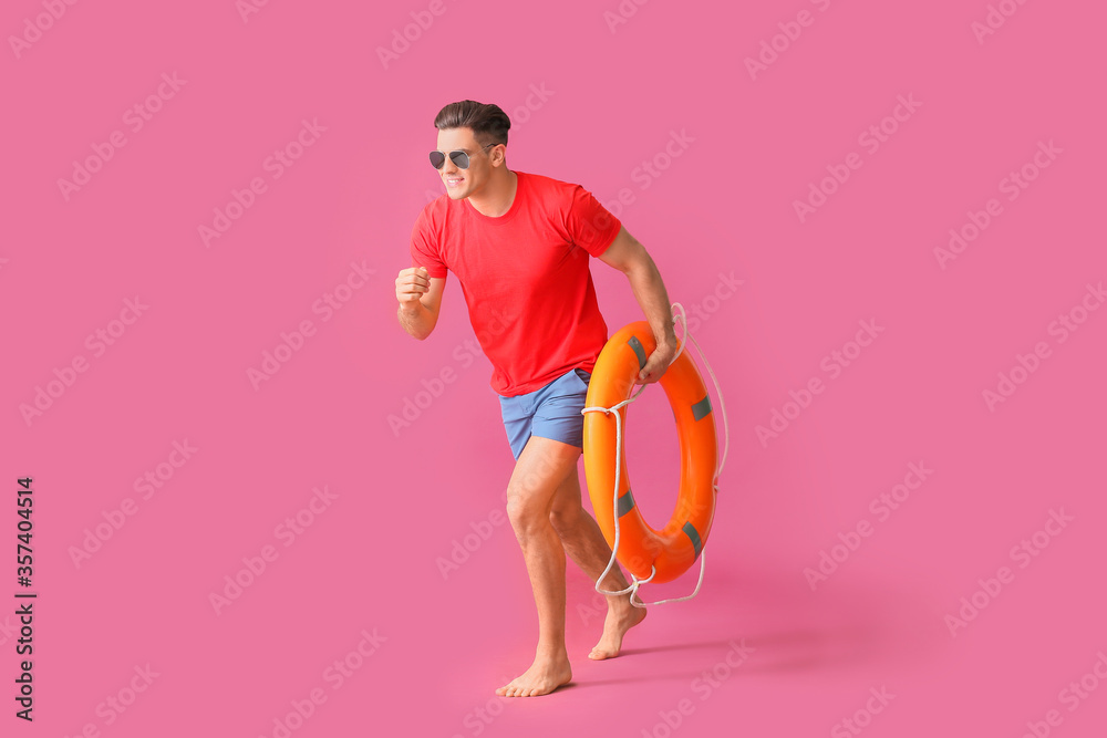 Running beach rescuer with lifebuoy on color background