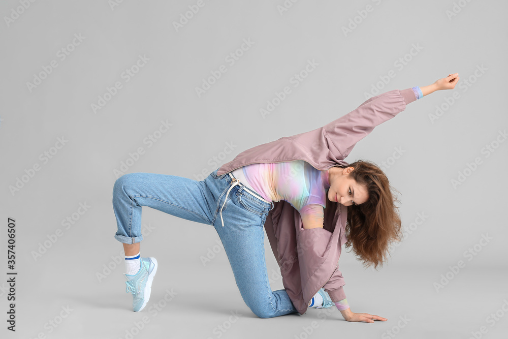 Beautiful female hip-hop dancer on grey background