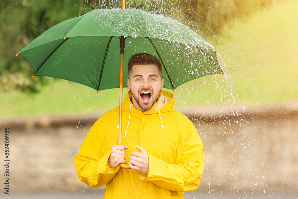 年轻人在户外打着雨伞，穿着雨衣