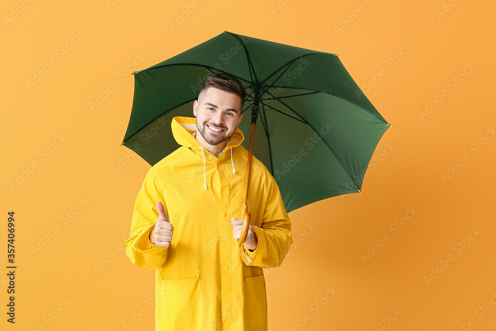 穿着雨衣、打着雨伞的年轻人在彩色背景上竖起大拇指