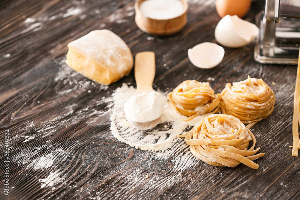 Raw pasta with flour and dough on table