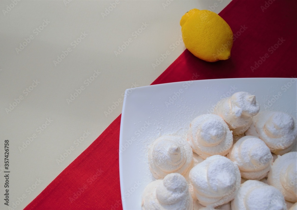 Composition at the junction of two backgrounds. A white square plate with homemade French meringues 