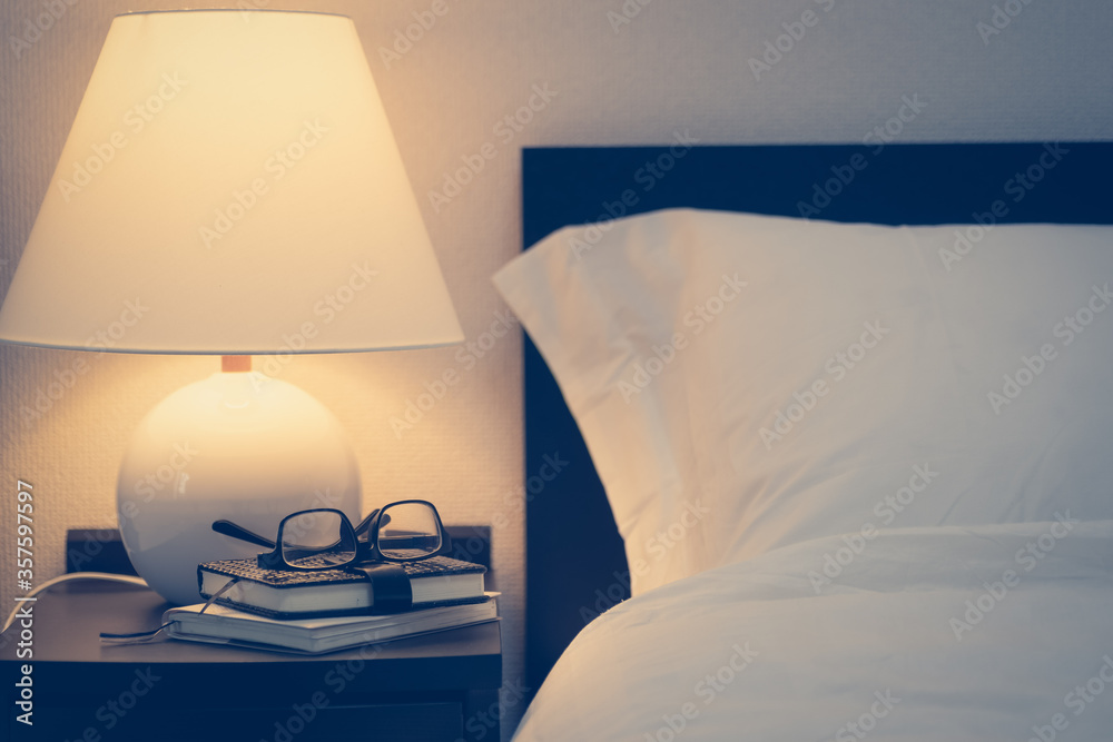 Bed headboard And lamps and books and glasses