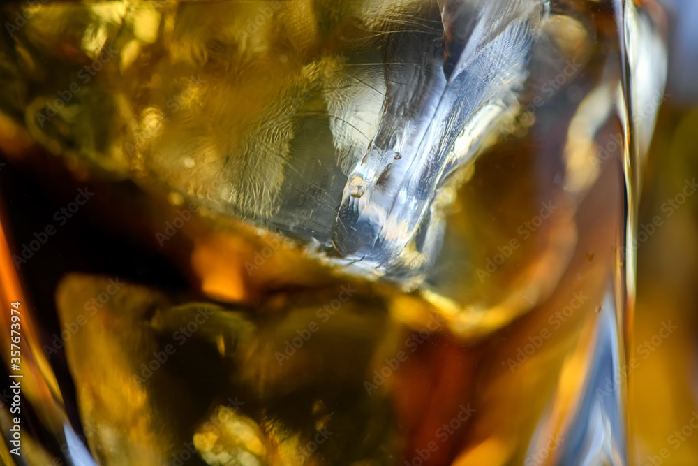 Pieces of ice cube in whiskey. Close up macro of Ice cubes in glass drink or another alcohol