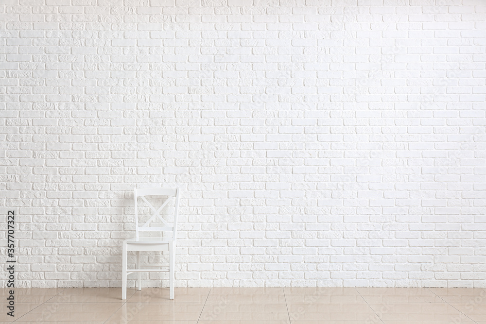 Chair near white brick wall in room