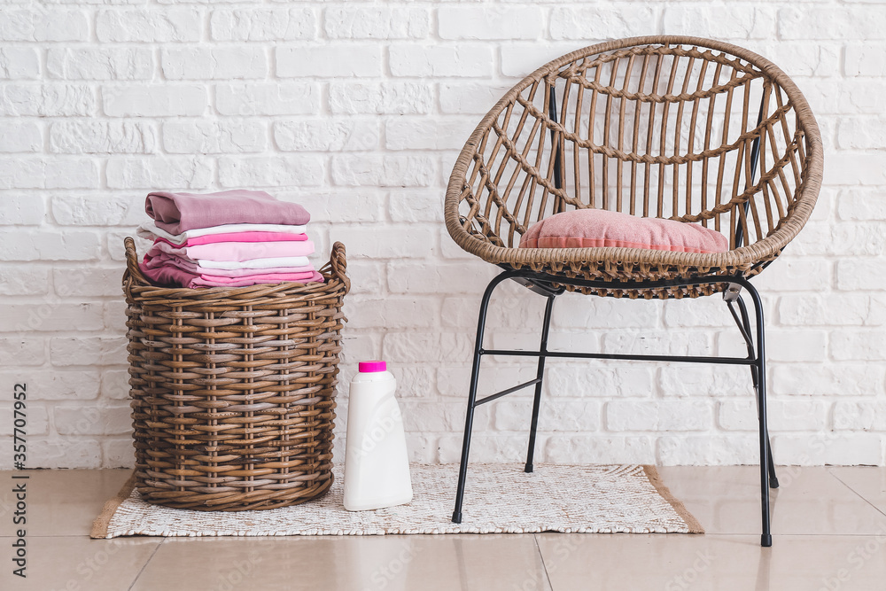 Basket with laundry and armchair in room