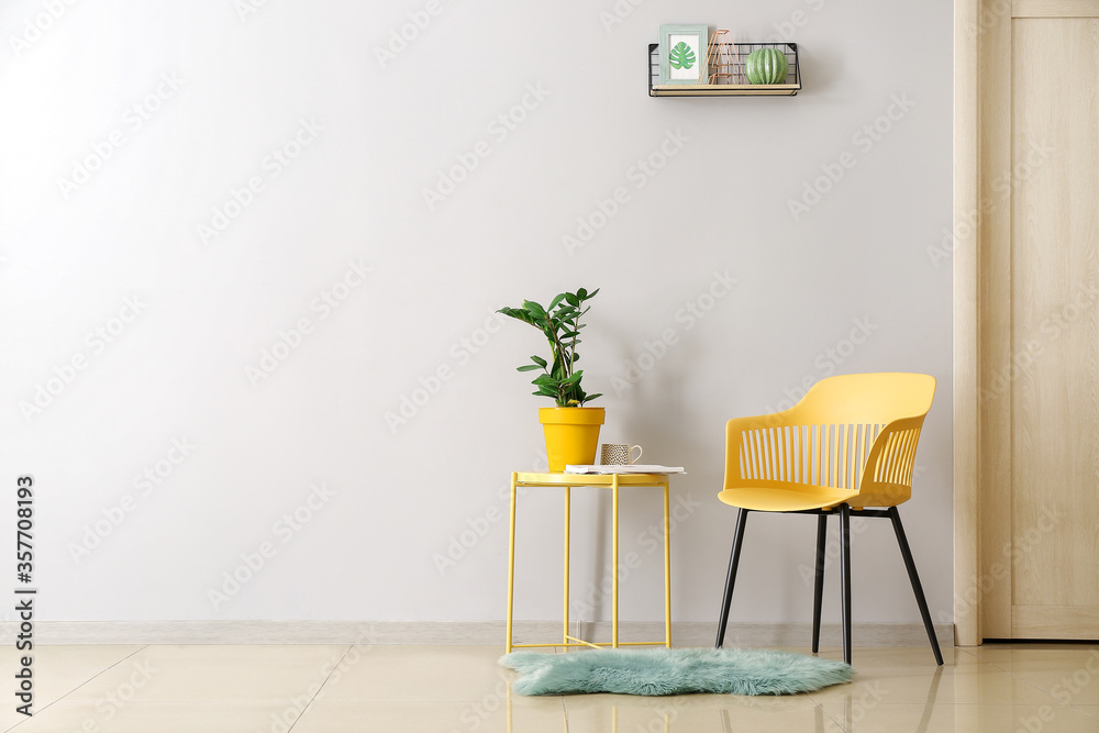 Stylish chair and table with houseplant in interior of living in room