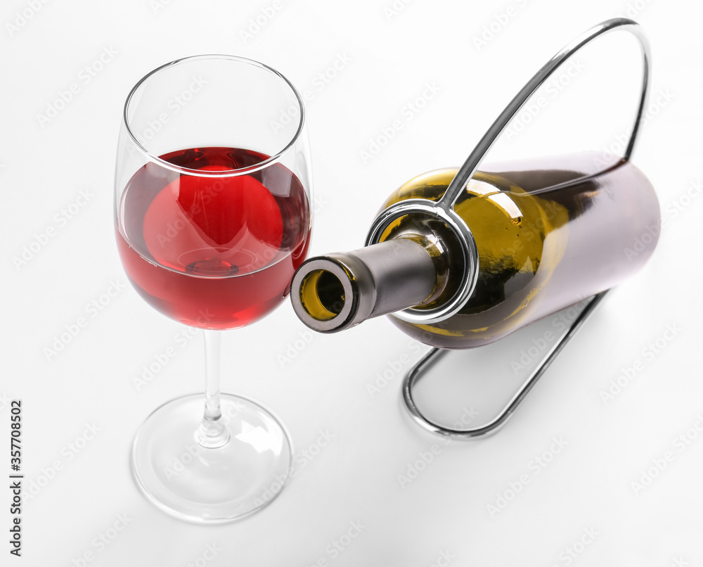 Holder with bottle and glass of wine on white background