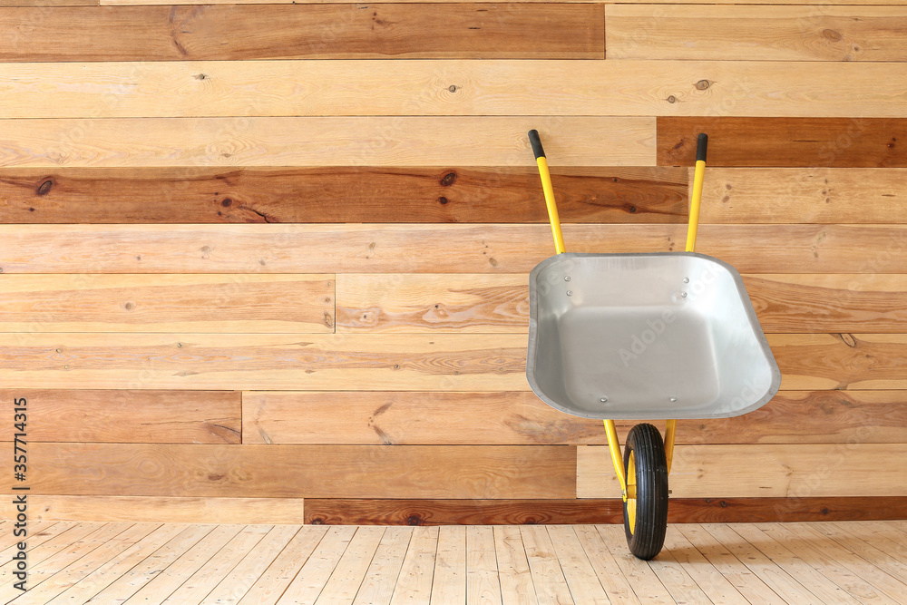 Empty wheelbarrow near wooden wall