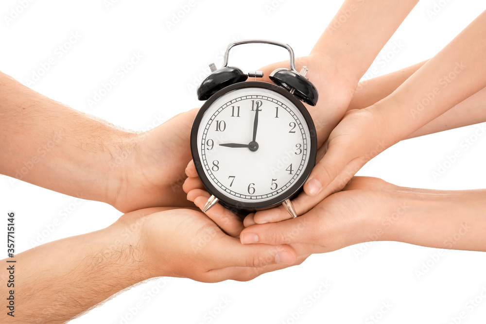 Hands of family with alarm clock on white background