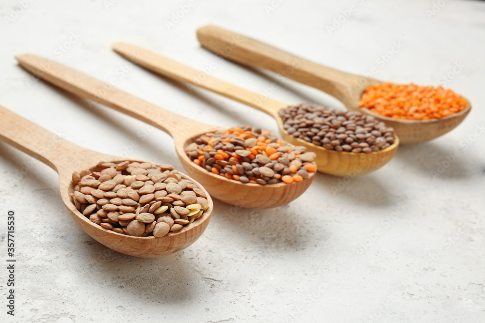 Spoons with lentils on white background