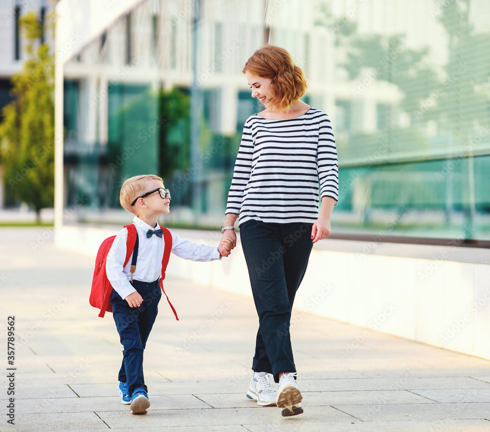 first day at school. mother leads  little child boy in grade.