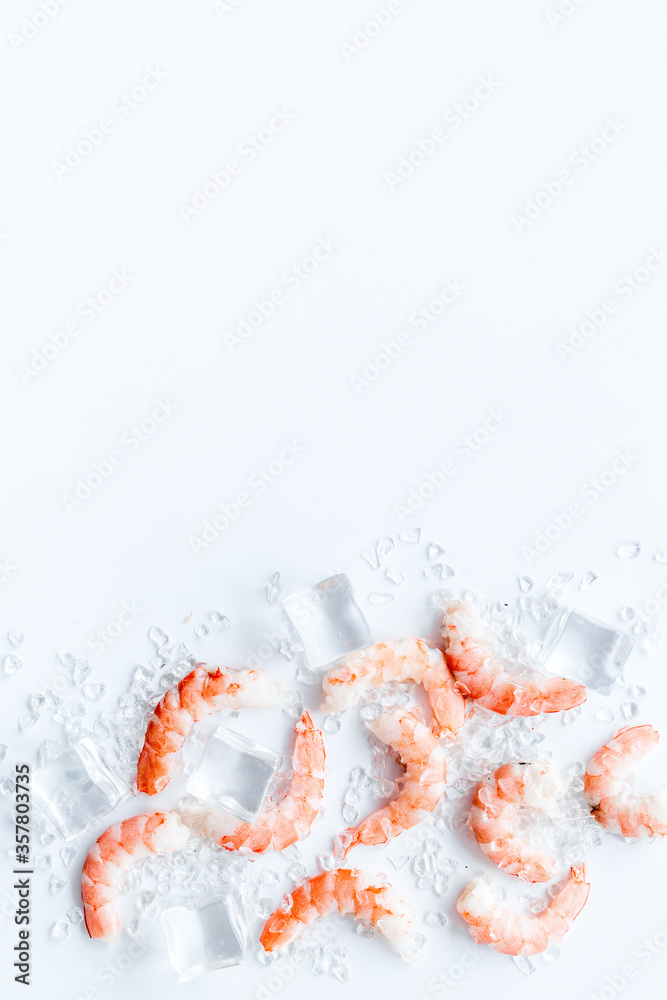 Shrimps - peeled, with ice - on white table frame copy space