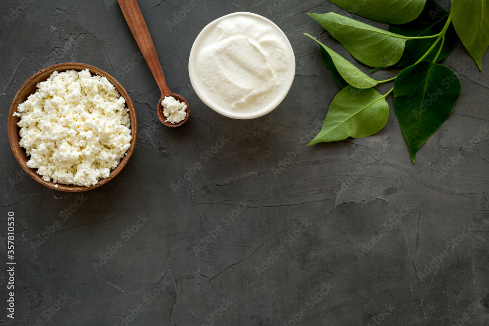 Cottage cheese in wooden bowl on black table top view copy space