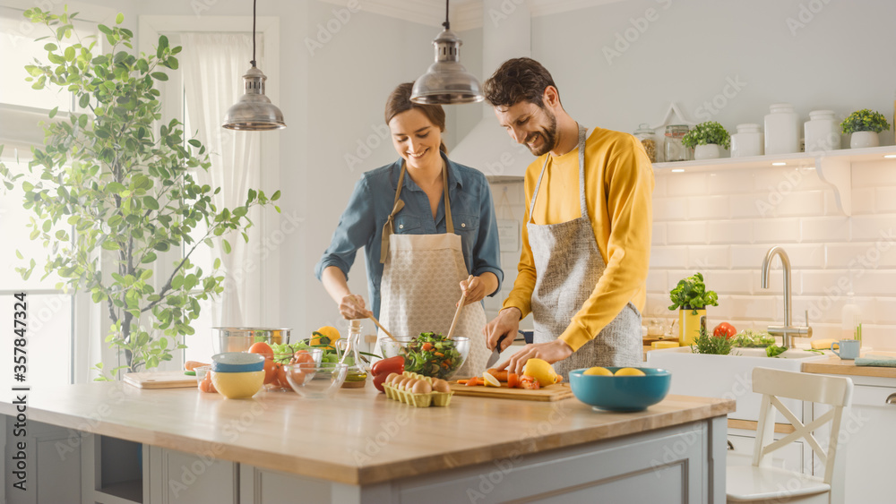 In Kitchen: Perfectly Happy Couple Preparing Healthy Food, Lots of Vegetables. Man Juggles with Frui