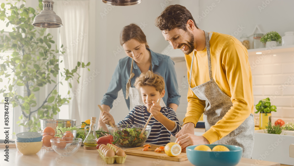 In the Kitchen: Mother, Father and Cute Little Boy Cooking Together Healthy Dinner. Parents Teach Li