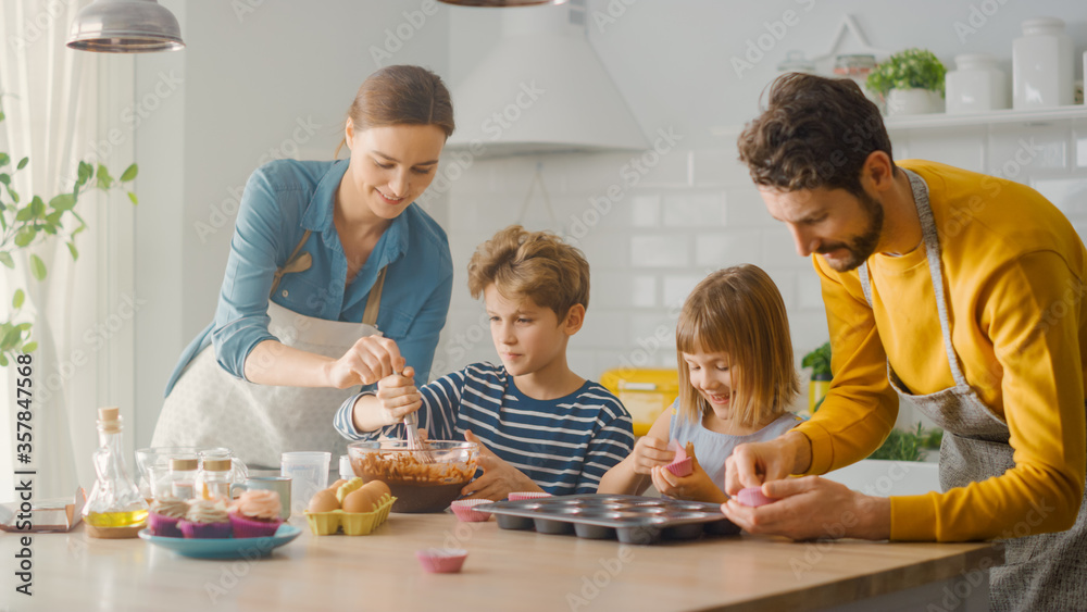 In the Kitchen: Family of Four Cooking Muffins Together. Mother and Daughter Mixing Flour and Water 