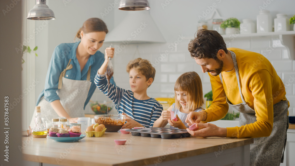 In the Kitchen: Family of Four Cooking Muffins Together. Mother and Daughter Mixing Flour and Water 