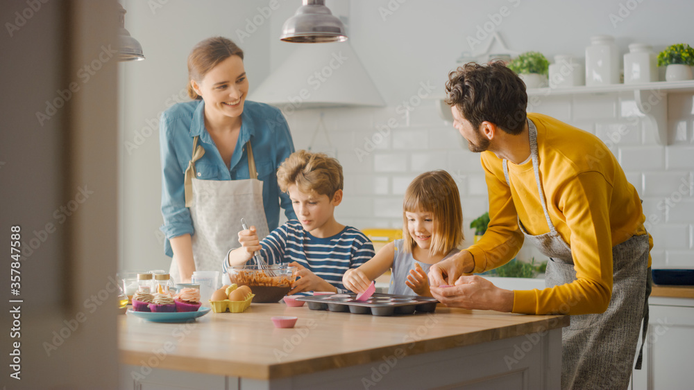 In the Kitchen: Family of Four Cooking Muffins Together. Mother and Daughter Mixing Flour and Water 