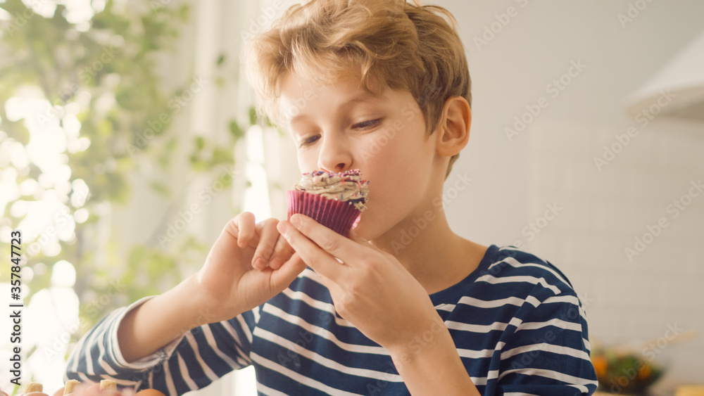 In the Kitchen: Adorable Boy Eats Creamy Cupcake with Frosting and Sprinkled Funfetti. Cute Hungry S