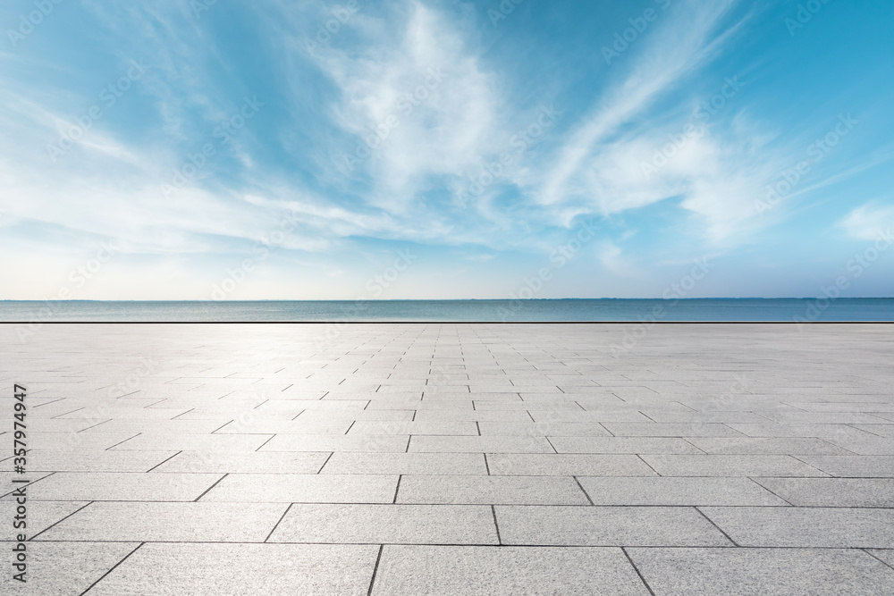 Empty square floor and lake under blue sky.