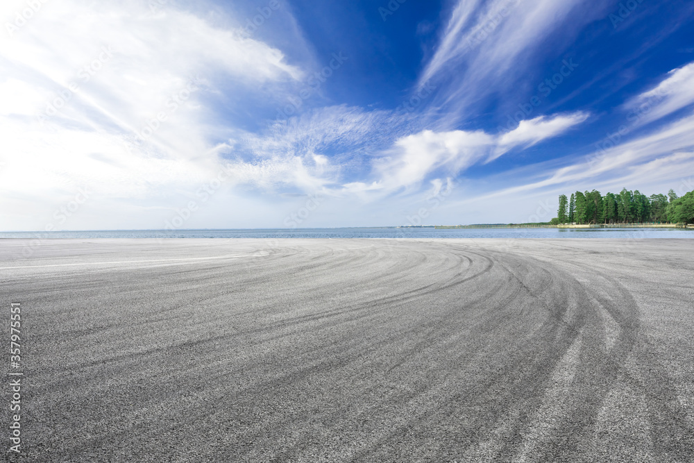 蓝天下空旷的柏油路和湖泊。