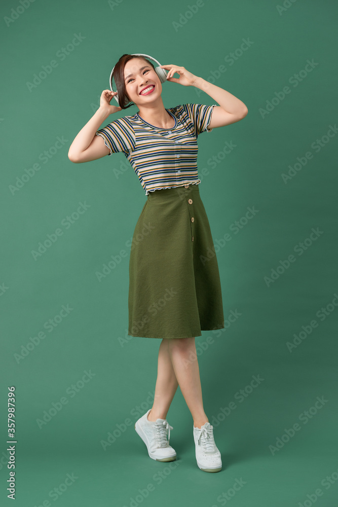 Music young girl dancing against isolated green background