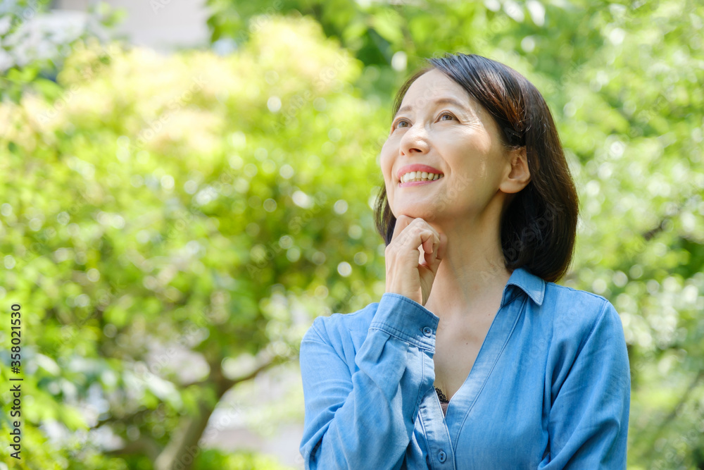 公園で考えごとをする中年女性