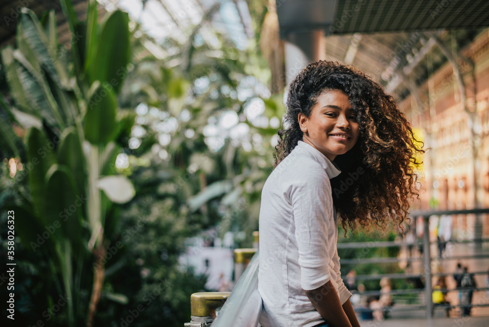 Portrait of a beautiful girl with curly hair, outdoors. Looking at camera.