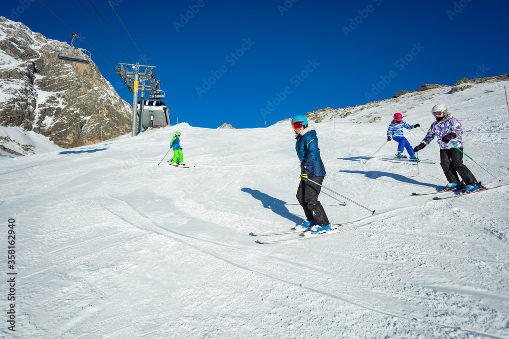 一群孩子一个接一个地在高山斜坡上滑雪