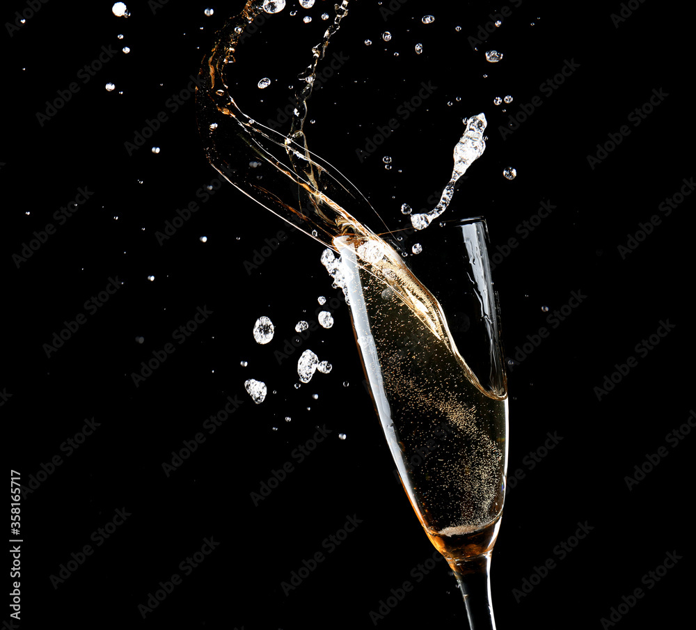 Glass of champagne with splash on dark background