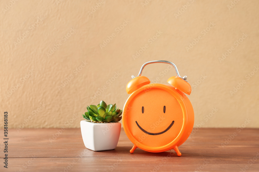 Alarm clock with drawn happy face on table