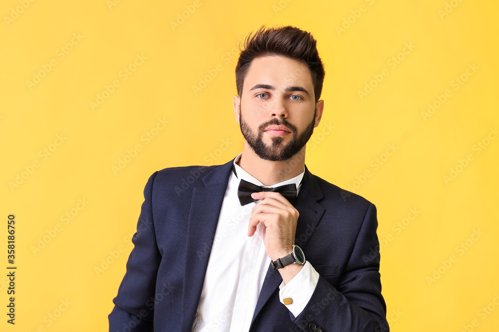 Young man in stylish suit on color background