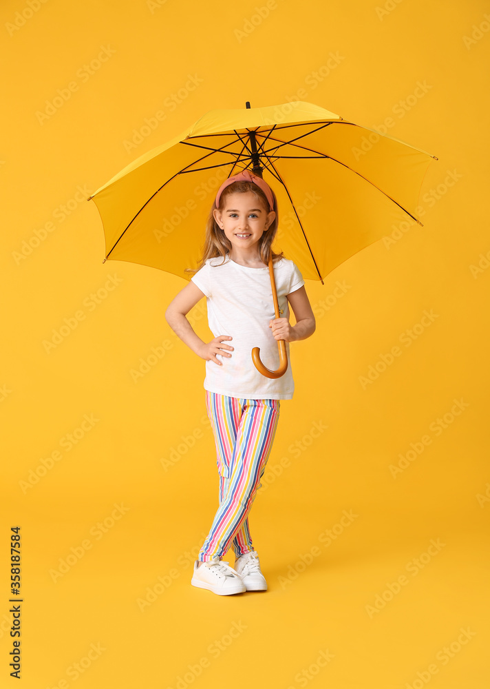 Cute little girl with umbrella on color background