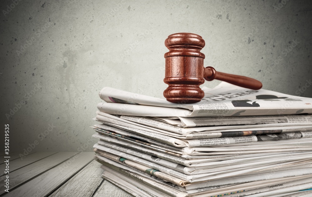 Stack of new fresh newspapers and wooden gavel on the desk