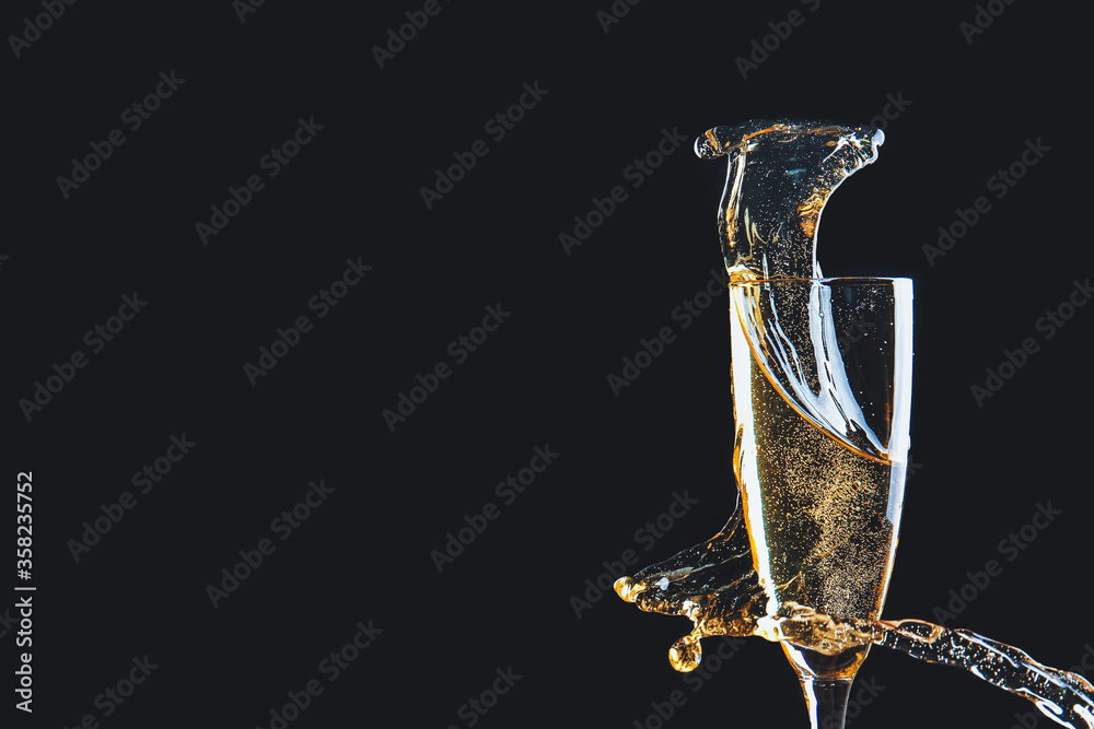 Glass of champagne with splash on dark background