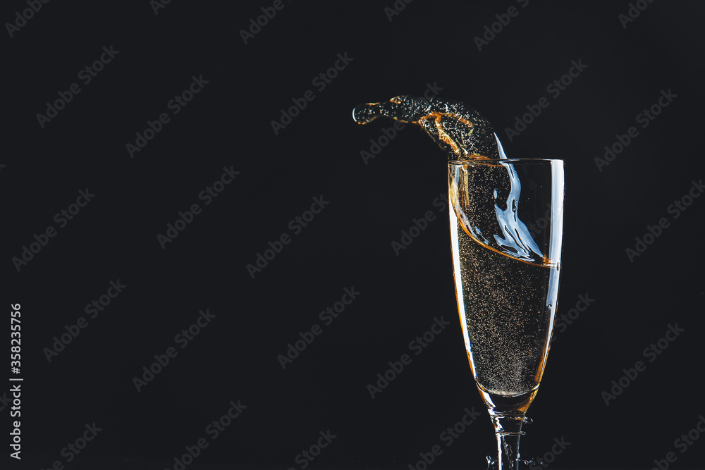 Glass of champagne with splash on dark background