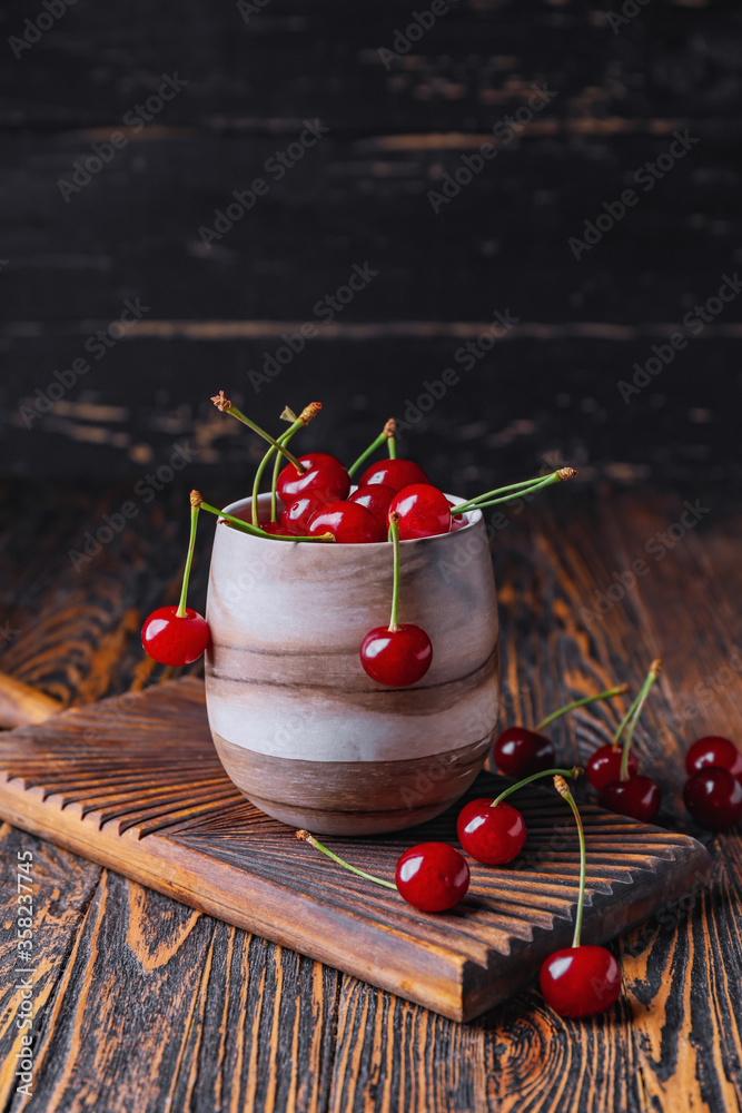 Cup with sweet cherry on table