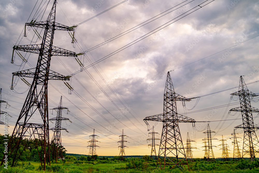 Electricity pylons and high-voltage power lines on the green grass. Power plant. Electrical power gr