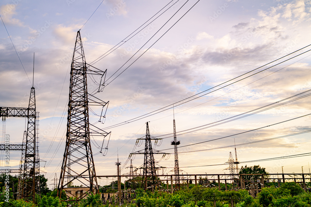 Electricity pylons against orange and yellow sunset. Selective focus.