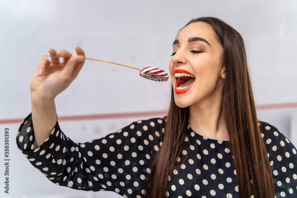 Woman bites lollipop with white healthy teeth. Beautiful lady with candy.