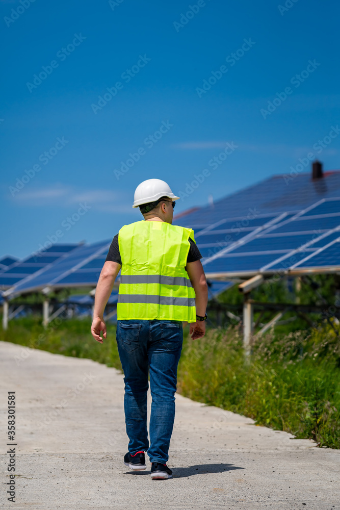 Technician checking efficiency of solar panel at solar power plant. View from the back.