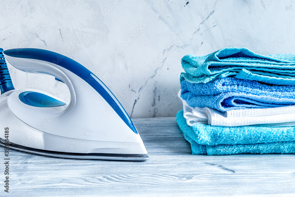 housekeeping set with towels and iron on laundry background