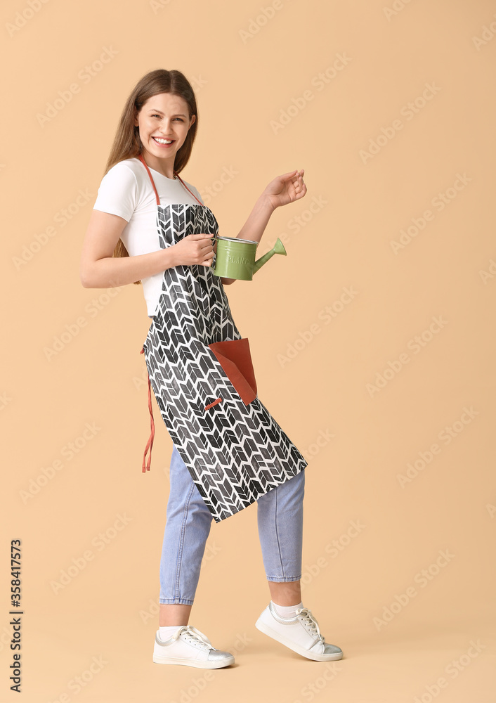 Young woman with watering can on color background