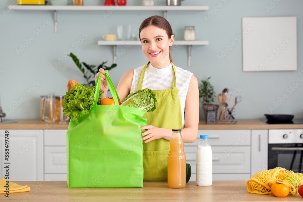 Woman unpacking fresh products from market in kitchen