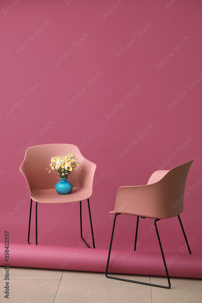 Vase with beautiful chamomiles and chairs indoors